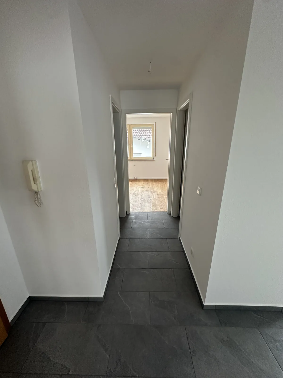 Sanierter Flur mit Sprechanlage und Blick ins Zimmer mit neuem Holzboden