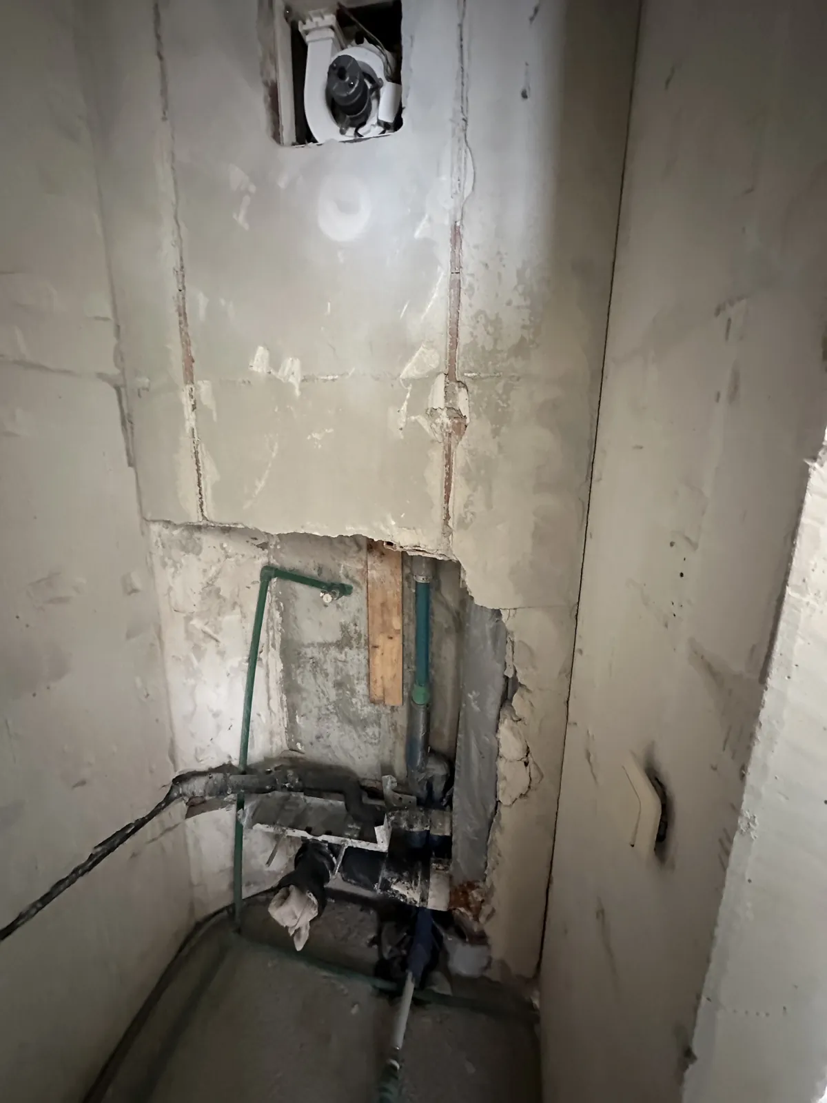 Freigelegte Wasserleitungen in der WC-Vorwand nach dem Rückbau im Bad