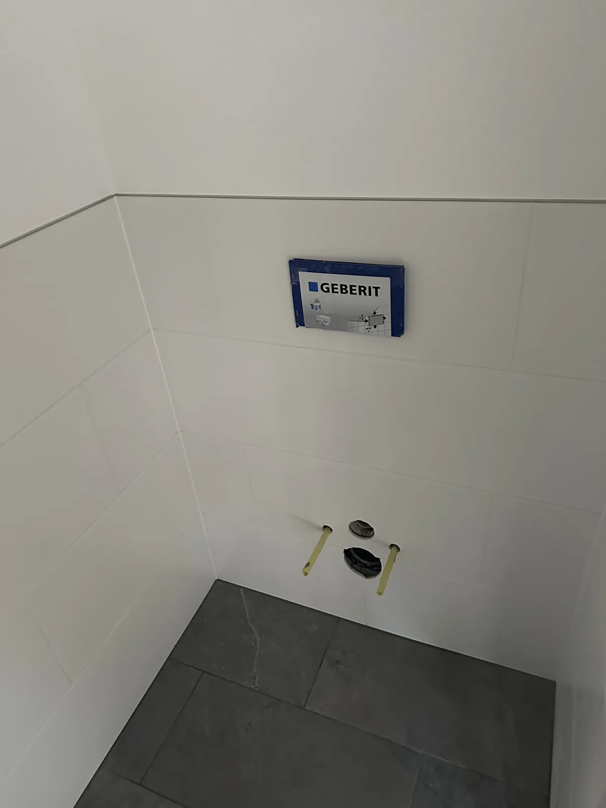 Neue WC-Vorwand mit Geberit-Element und weißen Wandfliesen im sanierten Bad