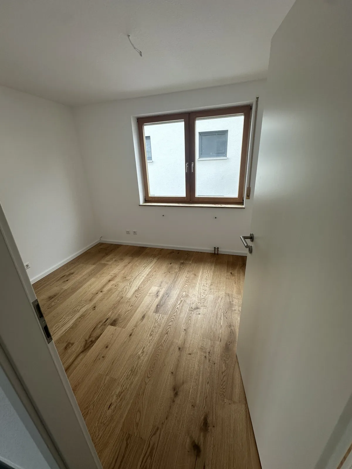 Fertiges Schlafzimmer mit neuem Holzboden und weißen Wänden