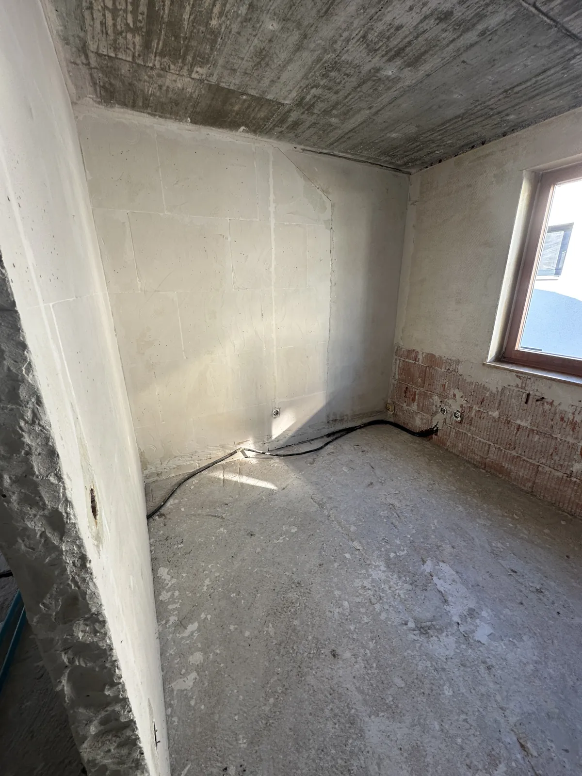 Zimmer im Rohzustand mit freigelegtem Mauerwerk und Rohboden