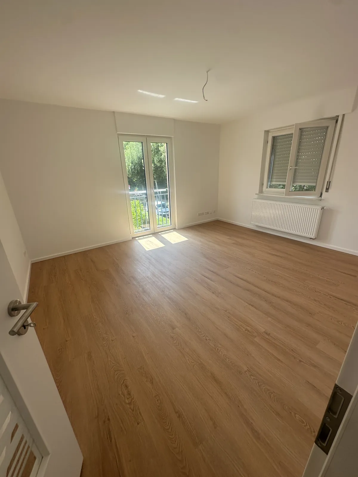 Saniertes Wohnzimmer mit neuem bodentiefem Fensterelement und hellem Holzboden
