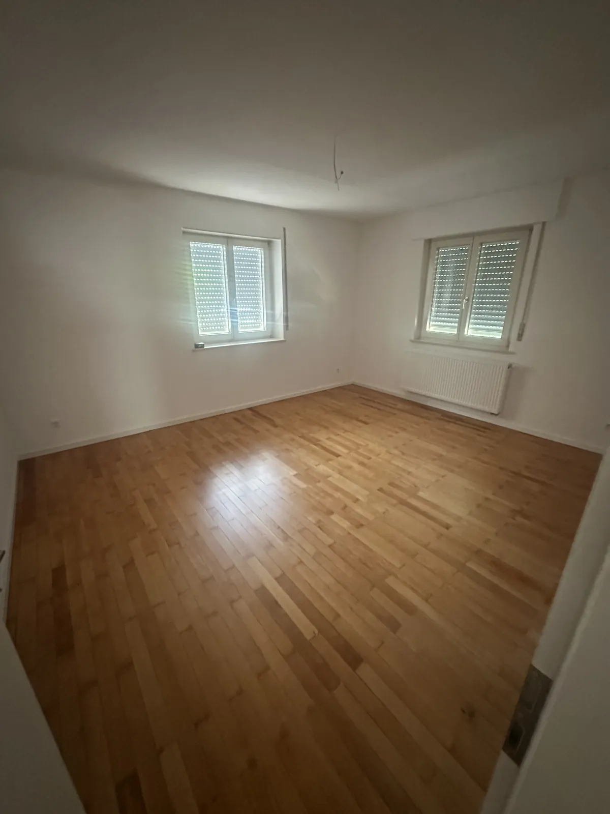 Renoviertes Zimmer mit aufgearbeitetem Parkett und weißen Wänden
