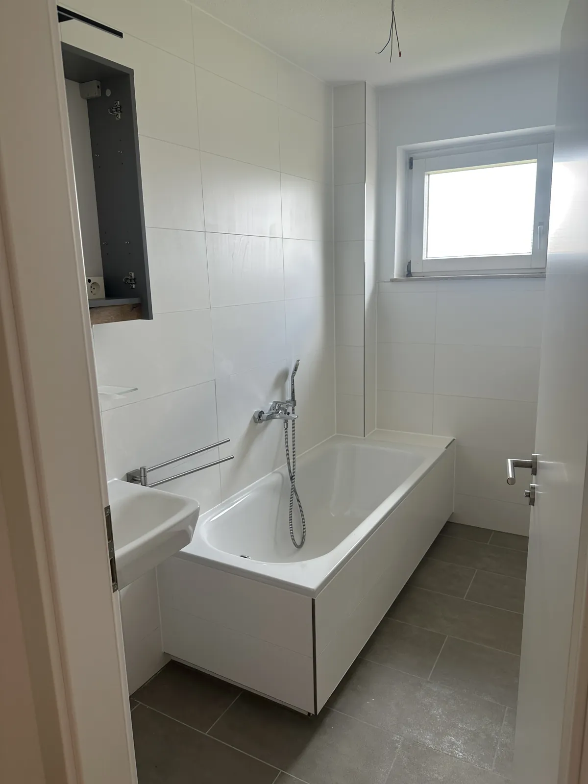 Neues Wannenbad mit weißen Fliesen, Badewanne und modernem Waschtisch